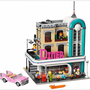 LEGO model of a diner with a pink car and people figures on a white background
