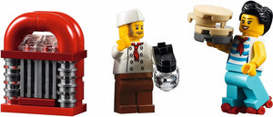 Two LEGO minifigures and a red jukebox on a white background
