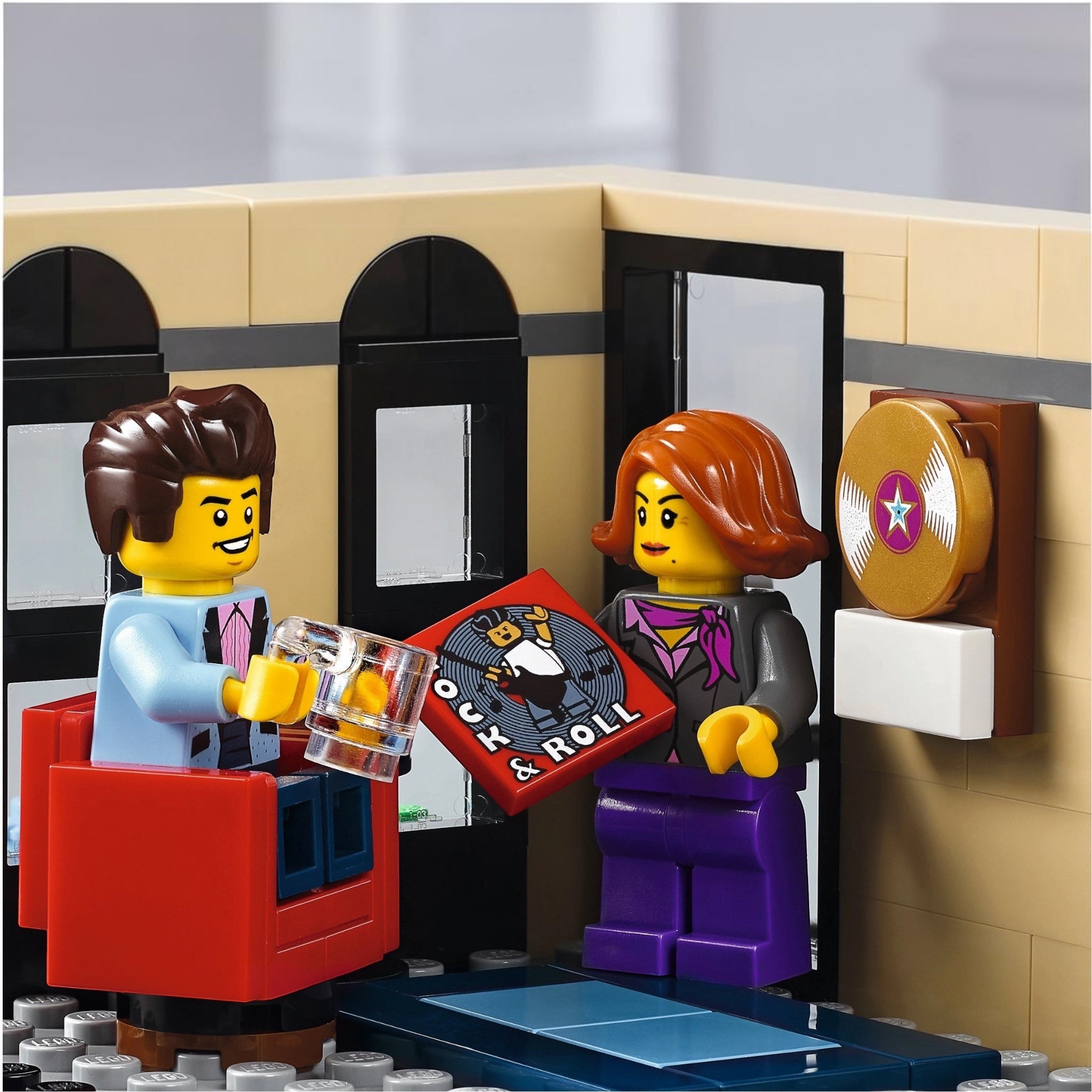Two LEGO figures in a room with a jukebox and wall decorations.