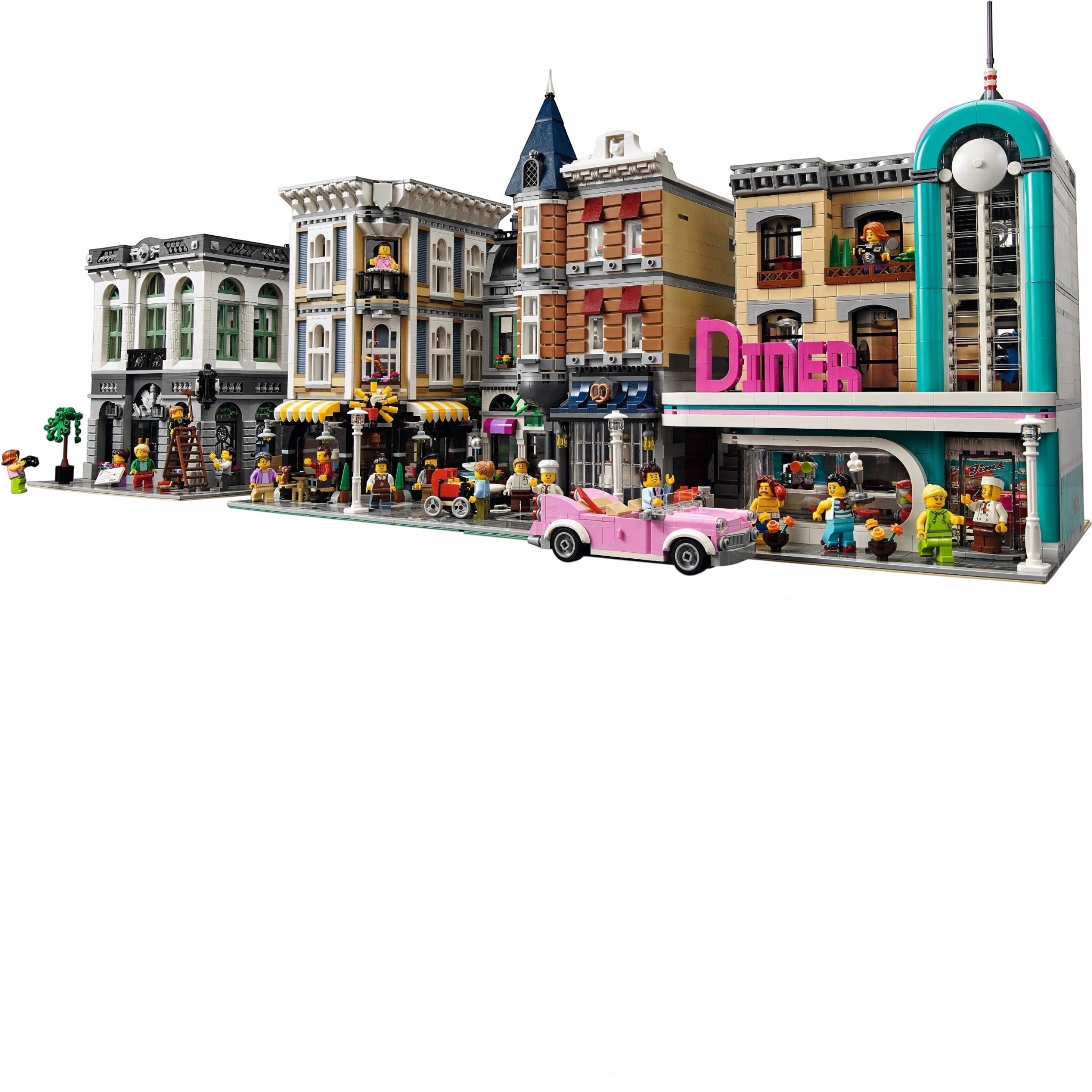 LEGO model of a city street with buildings and a pink car.