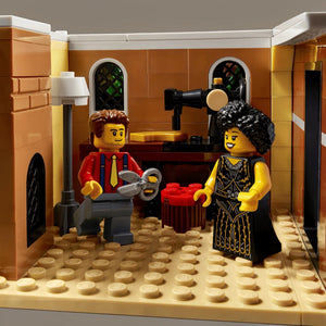 Two LEGO figures in a kitchen setting with a coffee machine and oven.