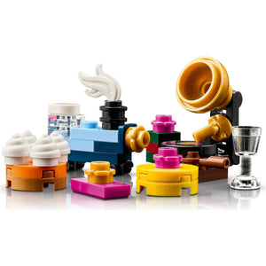 [built-detail] A colorful LEGO-style toy set arranged on a white studio background, featuring a blue body, yellow and orange parts, white and brown details, a clear glass-like cup, and small decorative pieces.