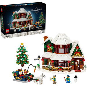 [box-set] LEGO Christmas Village Holiday House set shown with its retail box, assembled snowy holiday cottage, decorated Christmas tree, sleigh with figures, and small accessory figures on a white background.