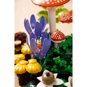 [lifestyle-person] Toy set with purple flower, yellow mushrooms, and red mushroom with white spots on a white background
