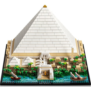 [built-angle] A detailed brick-built model of the Great Pyramid of Giza, featuring a large white brick pyramid, beige sandstone base, green palm trees, blue water, and small toy boats, shown on a plain white background.
