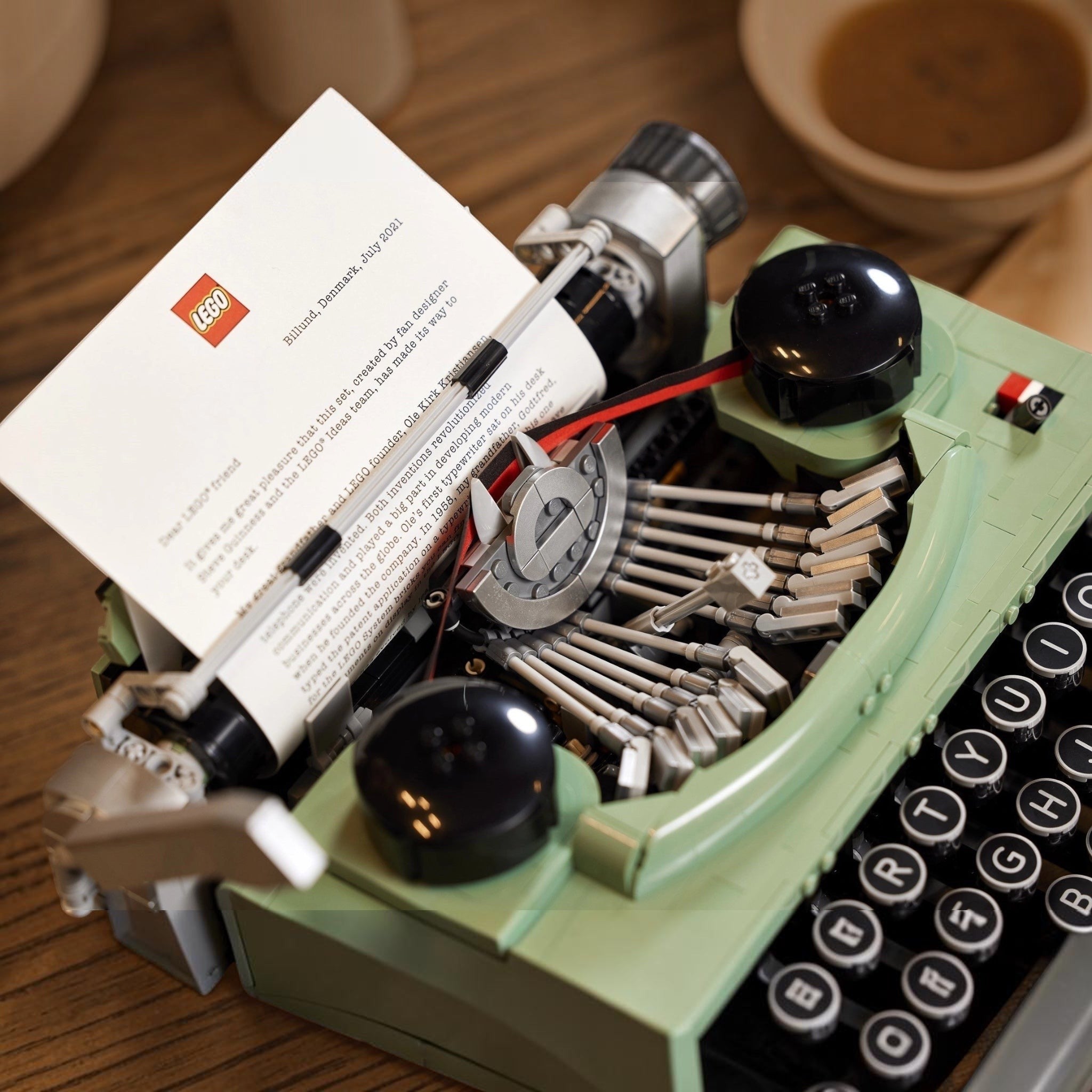 Green typewriter with a LEGO book on a wooden surface