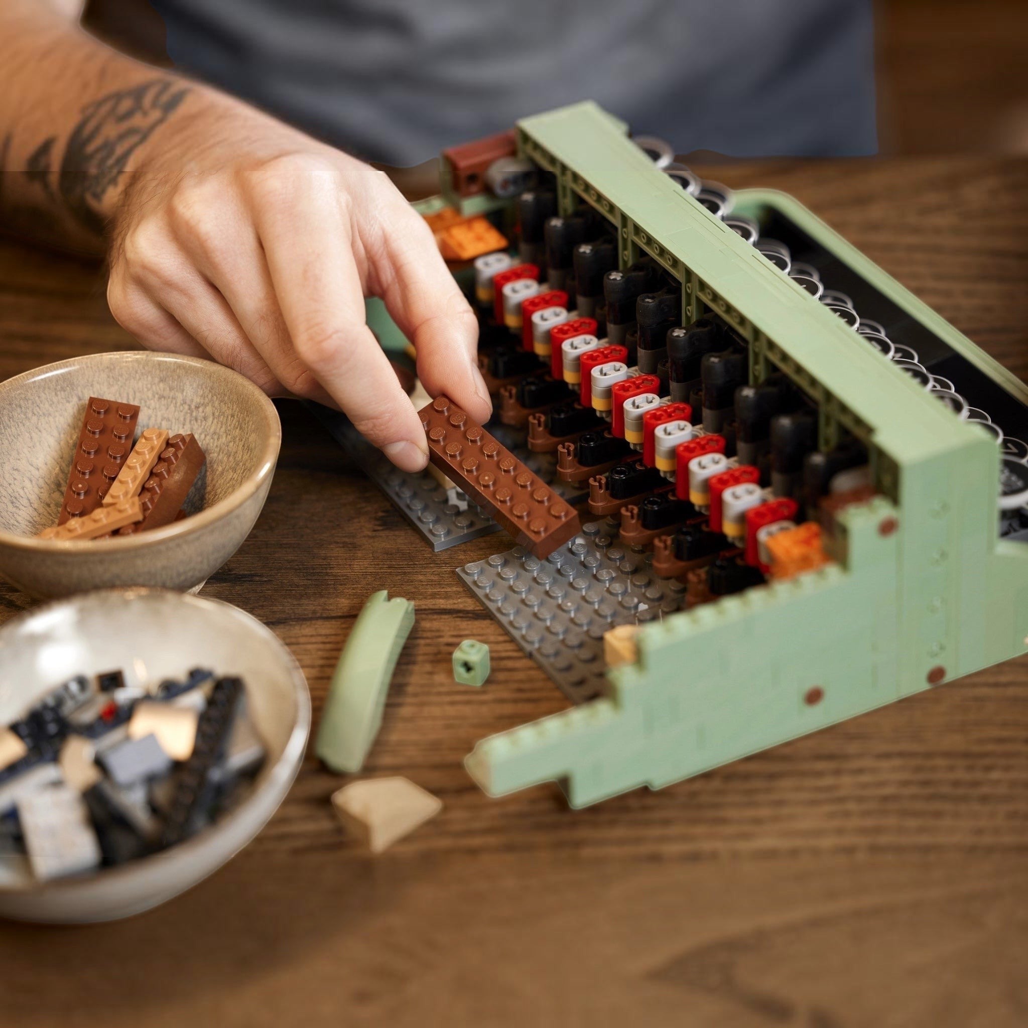 Hand building a lego model on a wooden table with ingredients nearby