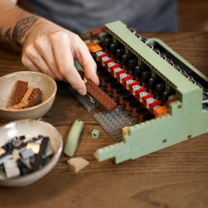 Hand building a lego model on a wooden table with ingredients nearby