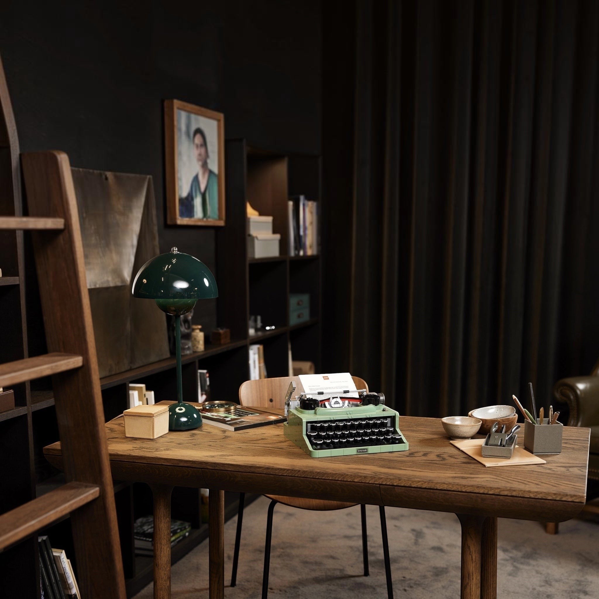 Vintage green typewriter on a wooden desk with bookshelves and decor in the background