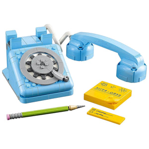 [built-detail] Toy telephone set with rotary dial, handset, pen, and sticky notes on a white background