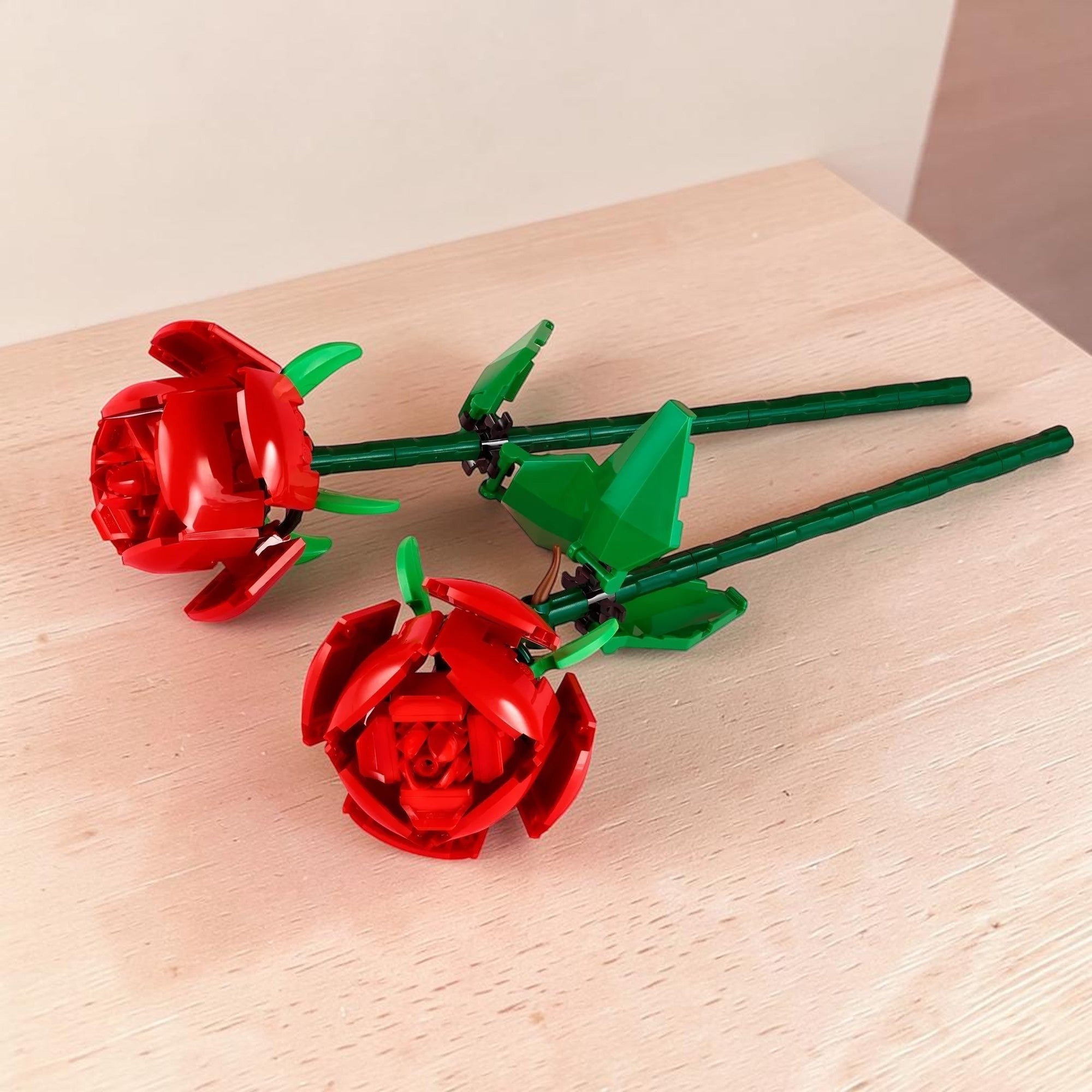 Red rose-shaped objects with green stems on a pink background
