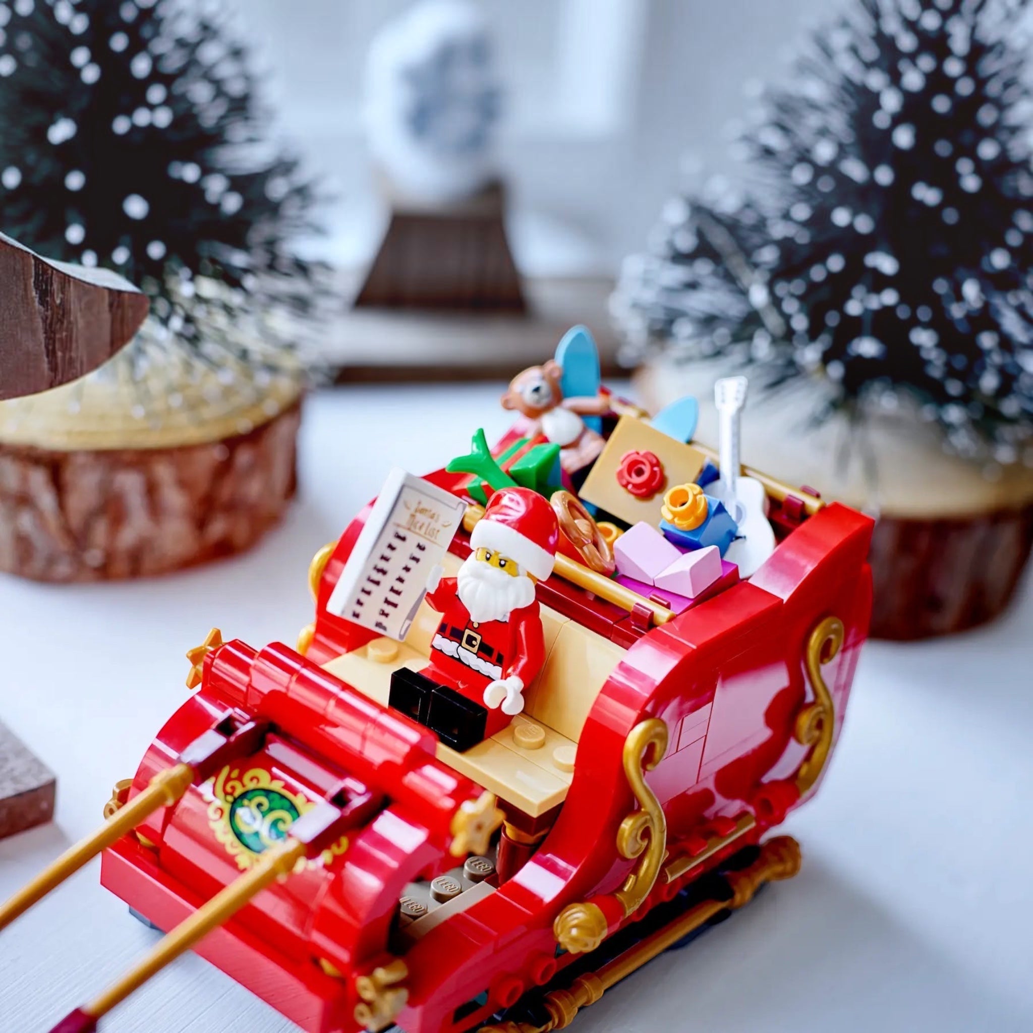 Toy sleigh with Santa Claus figure and Christmas decorations on a white surface.