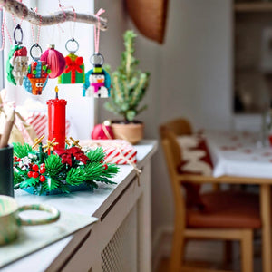 Decorative Christmas wreath with candles and ornaments on a kitchen counter.
