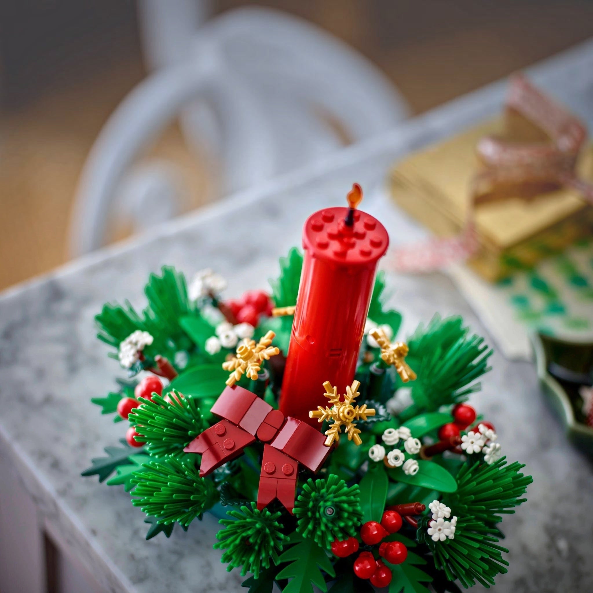 Christmas wreath made of LEGO bricks with a red candle on a marble surface.