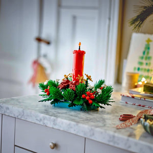 Decorative Christmas arrangement with a red candle on a marble surface.