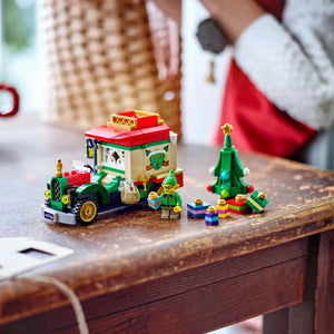 Christmas-themed LEGO set with a train, trees, and figures on a wooden surface.