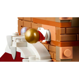 [built-detail] Close-up of a LEGO brick building set featuring orange and brown bricks, white brick structures, a gold ball, and a red accent piece on a white background.