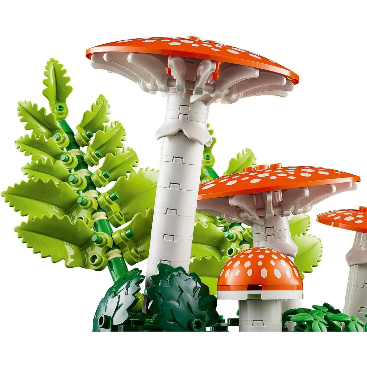 [built-detail] LEGO brick building set featuring three mushroom structures with orange caps, white stems, and green leaves and foliage on a plain white background.