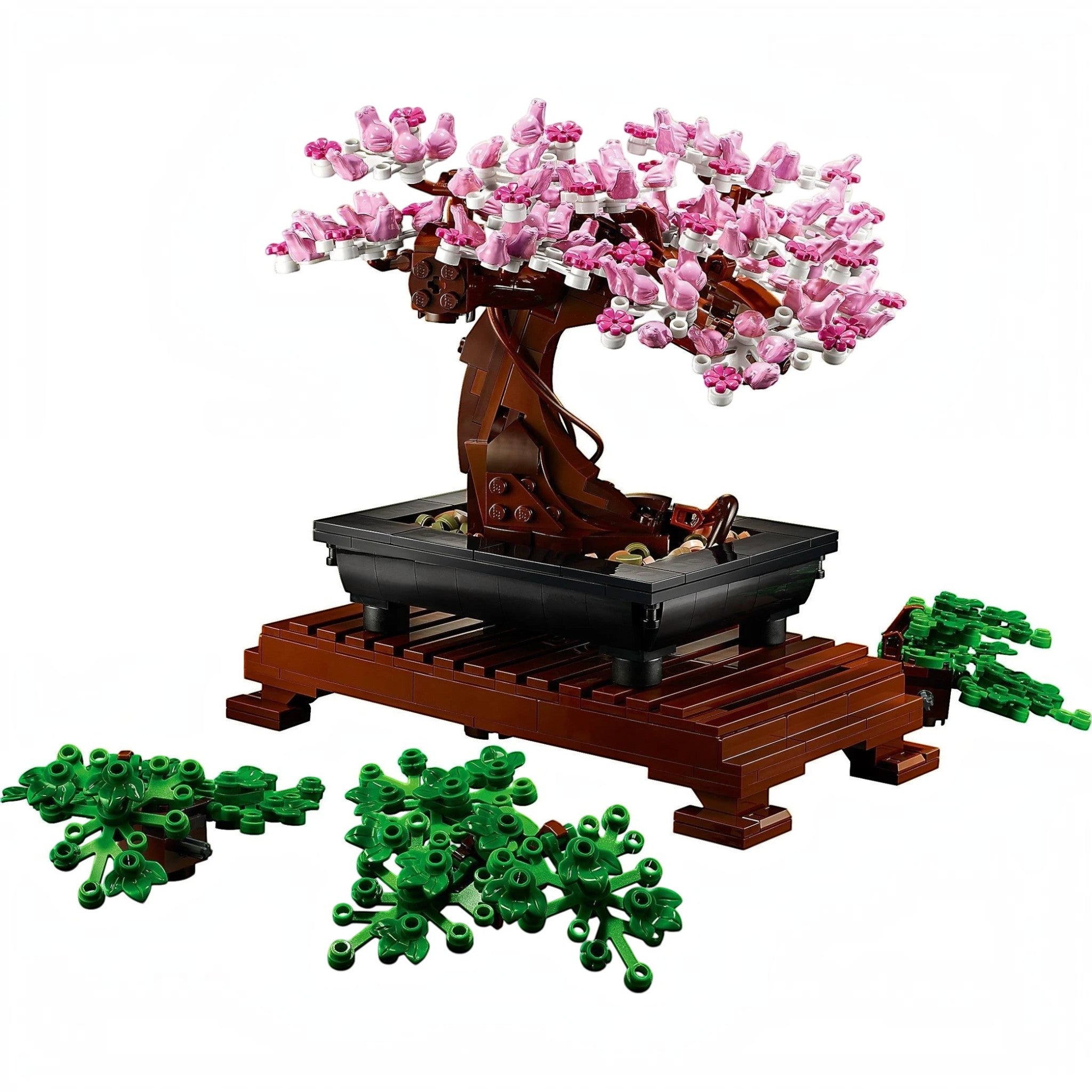 A Brick Apart LEGO Bonsai Tree model with pink cherry blossoms, rectangular pot, and wooden stand with extra green leaves.
