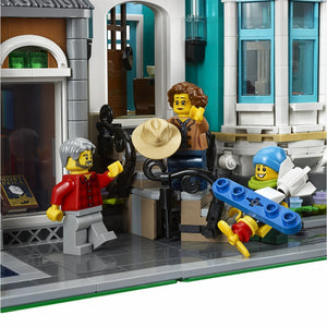 A Brick Apart LEGO Creator Expert Bookshop set featuring three minifigures interacting on a detailed sidewalk scene.