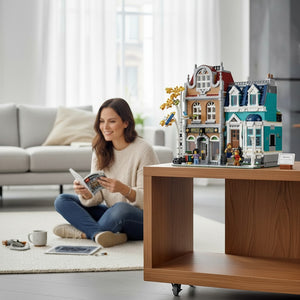 A Brick Apart LEGO Creator Expert Bookshop modular building set displayed on a wooden table with a woman reading nearby