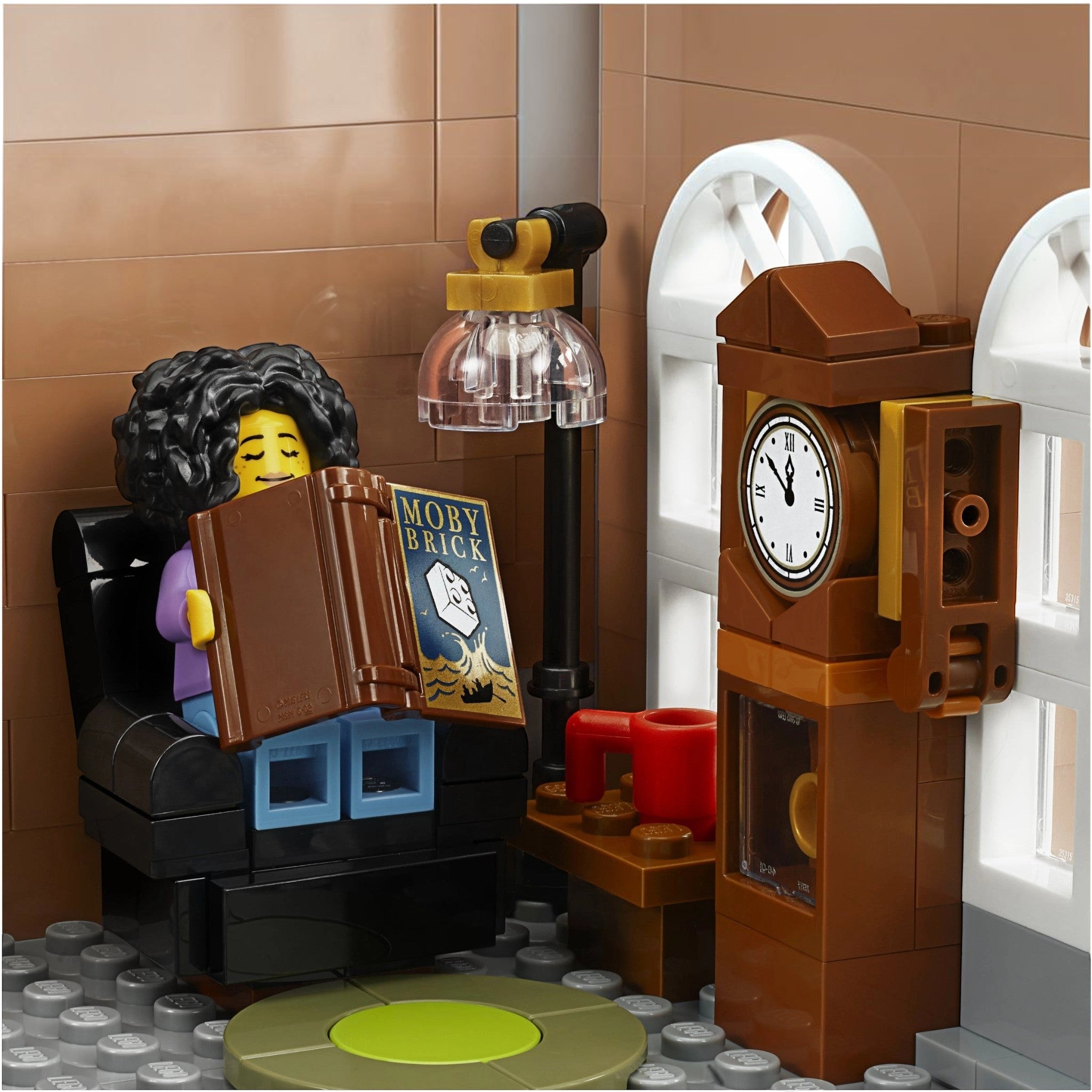 A Brick Apart LEGO Creator Expert Bookshop interior with a minifigure reading a Moby Brick book in a cozy armchair.