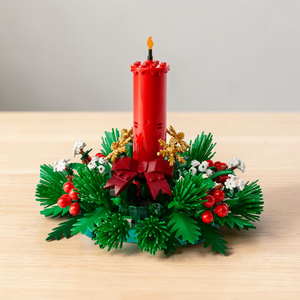 [lifestyle-shelf-built] A Brick Apart LEGO Christmas table decoration featuring a red candle, green foliage, red berries, and golden stars.
