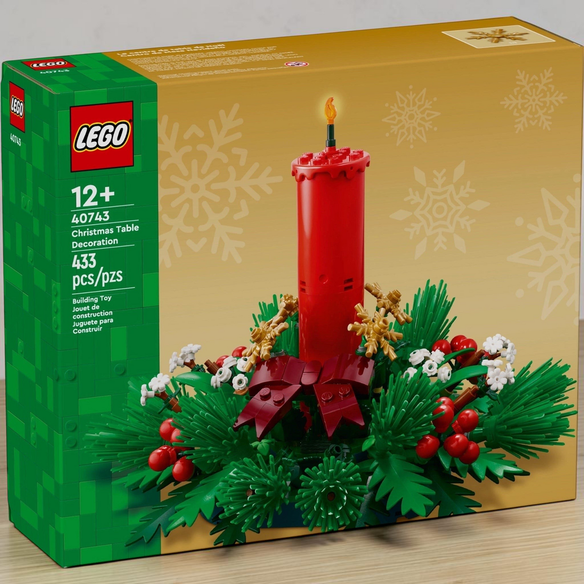 [lifestyle-shelf-box] A Brick Apart LEGO Christmas Table Decoration building kit box featuring a red candle, berries, and green foliage.