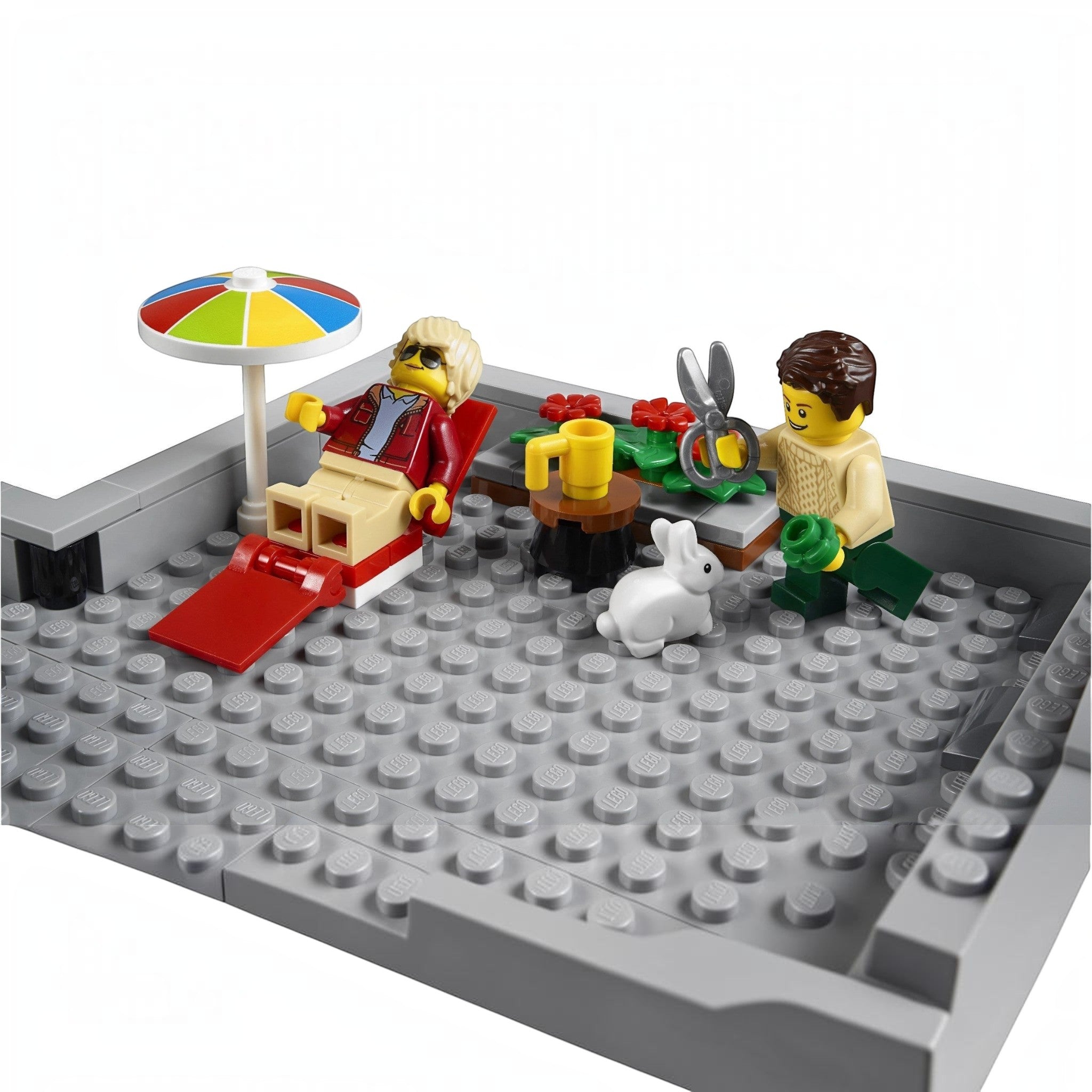 A Brick Apart LEGO Corner Garage rooftop terrace with two minifigures, a sun lounger, umbrella, and a white bunny.