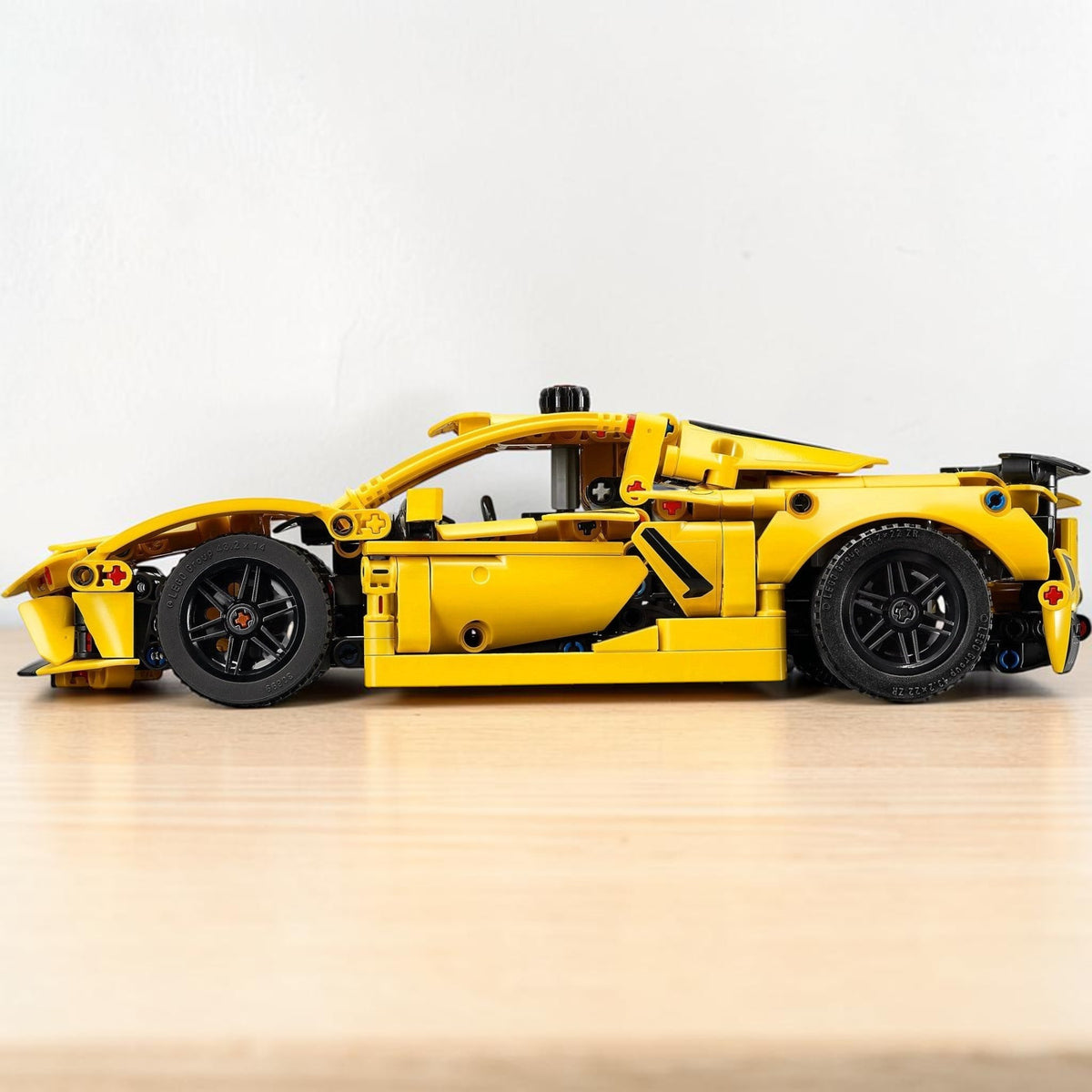 [lifestyle-shelf-built] A Brick Apart LEGO Technic Chevrolet Corvette Stingray model in bright yellow, shown from a side profile view.