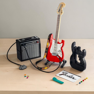[lifestyle-shelf-box] A Brick Apart LEGO Fender Stratocaster set featuring a red guitar, black amplifier, and alternate black guitar body.