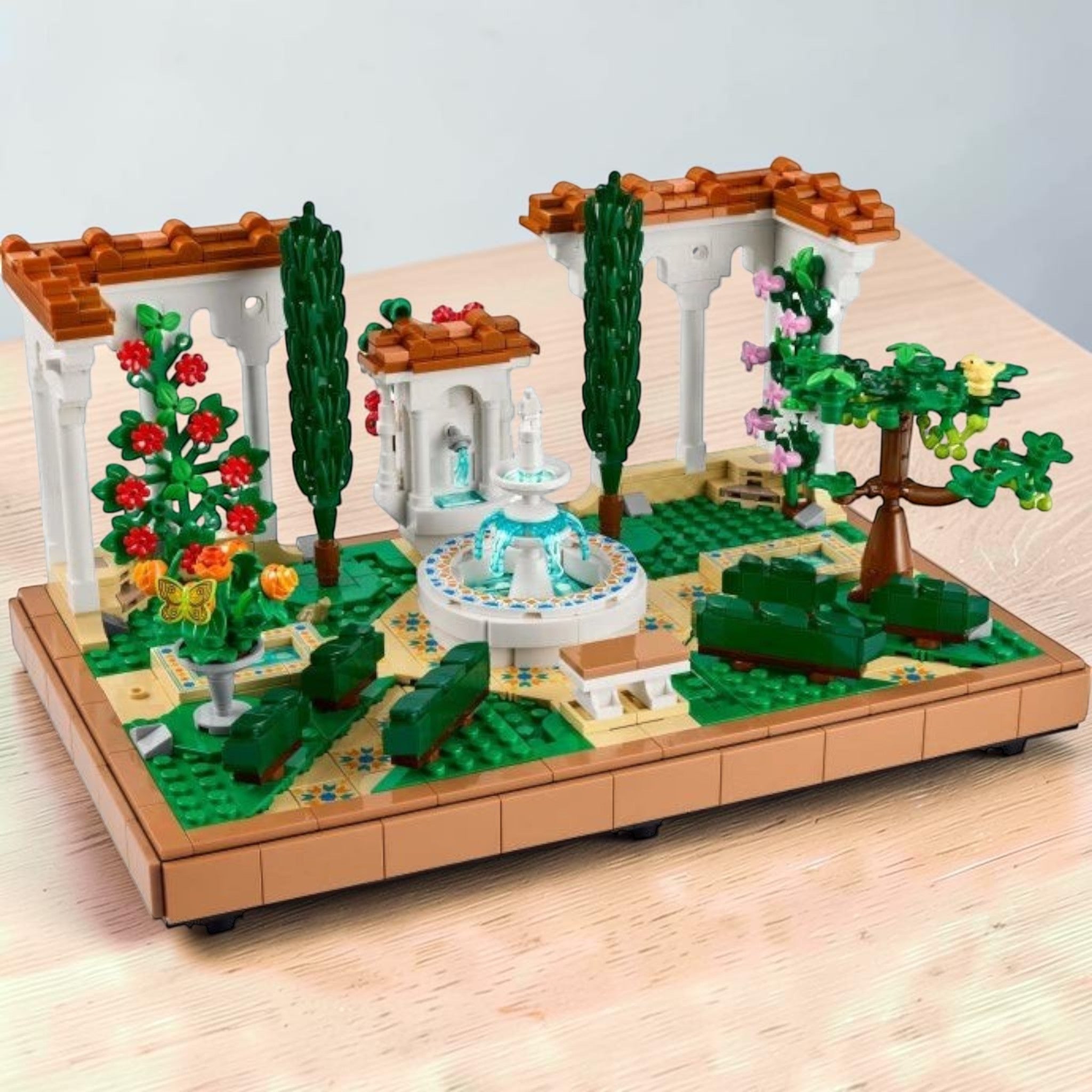 A Brick Apart LEGO Icons Fountain Garden set featuring a tiered fountain, white pergolas, cypress trees, and flowers.