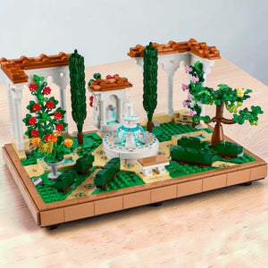A Brick Apart LEGO Icons Fountain Garden set featuring a tiered fountain, white pergolas, cypress trees, and flowers.