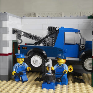 A Brick Apart LEGO Corner Garage mechanic minifigures working on a blue tow truck in the workshop