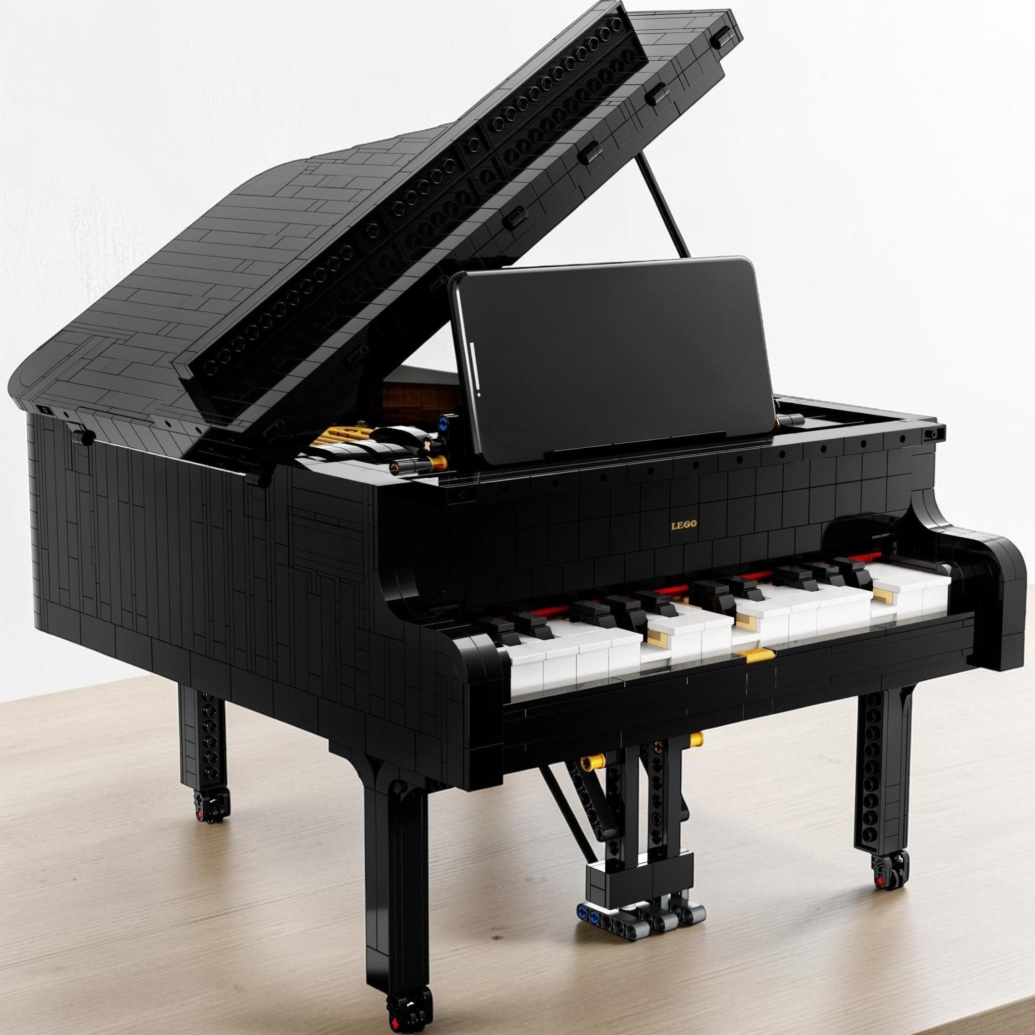 A Brick Apart LEGO Ideas Grand Piano model with a black finish, open lid, and smartphone mounted on the music stand.