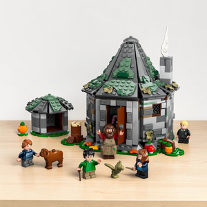 [lifestyle-shelf-built] A Brick Apart LEGO Harry Potter Hagrid's Hut set with minifigures, Fang the dog, and Norbert the dragon on a table.
