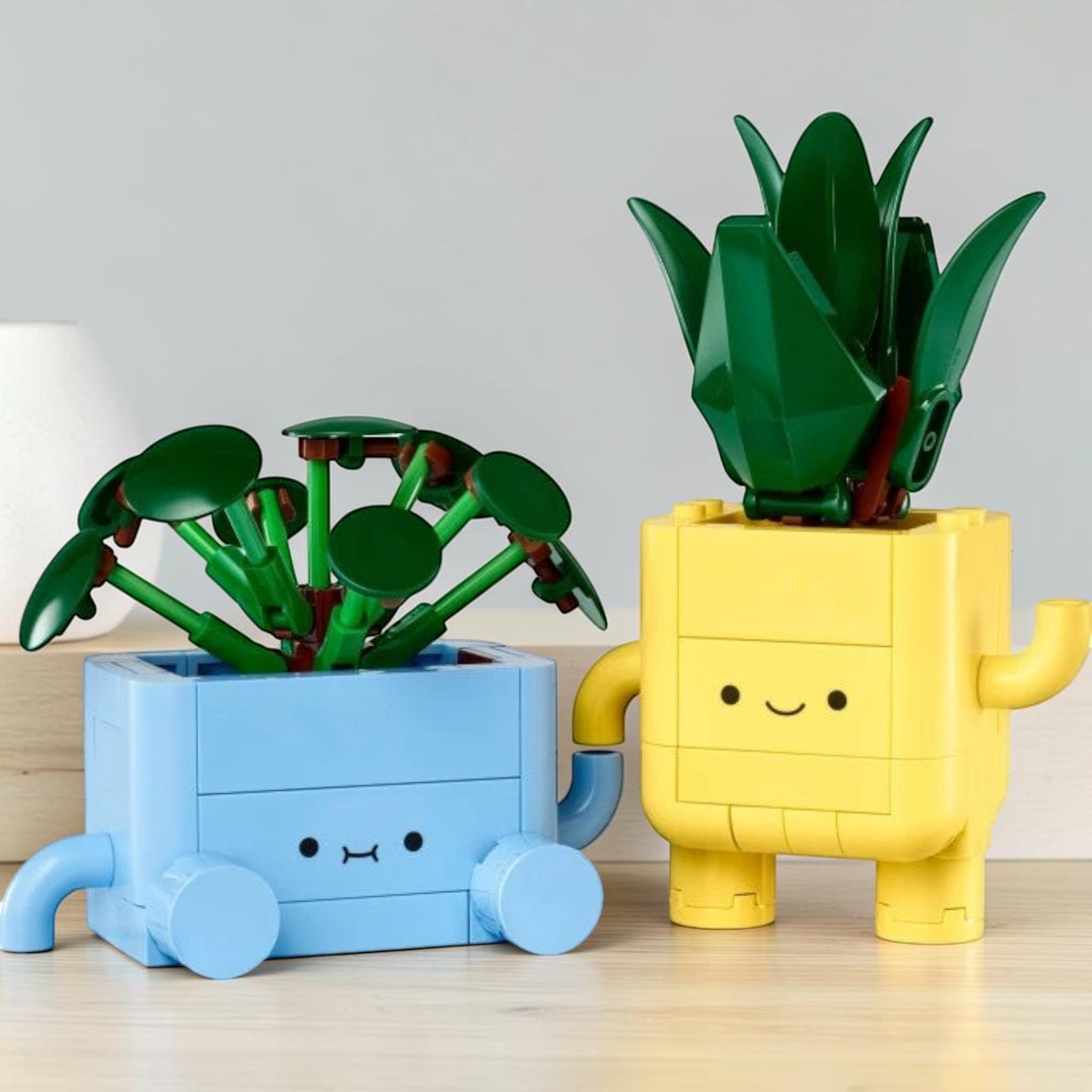 A Brick Apart LEGO Botanicals Happy Plants set featuring a green dracaena and pilea in blue and yellow cartoon pots.