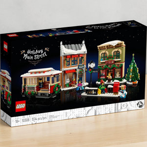 [lifestyle-shelf-box] A Brick Apart LEGO Icons Holiday Main Street set box featuring a festive streetcar, toy store, music shop, and tree.