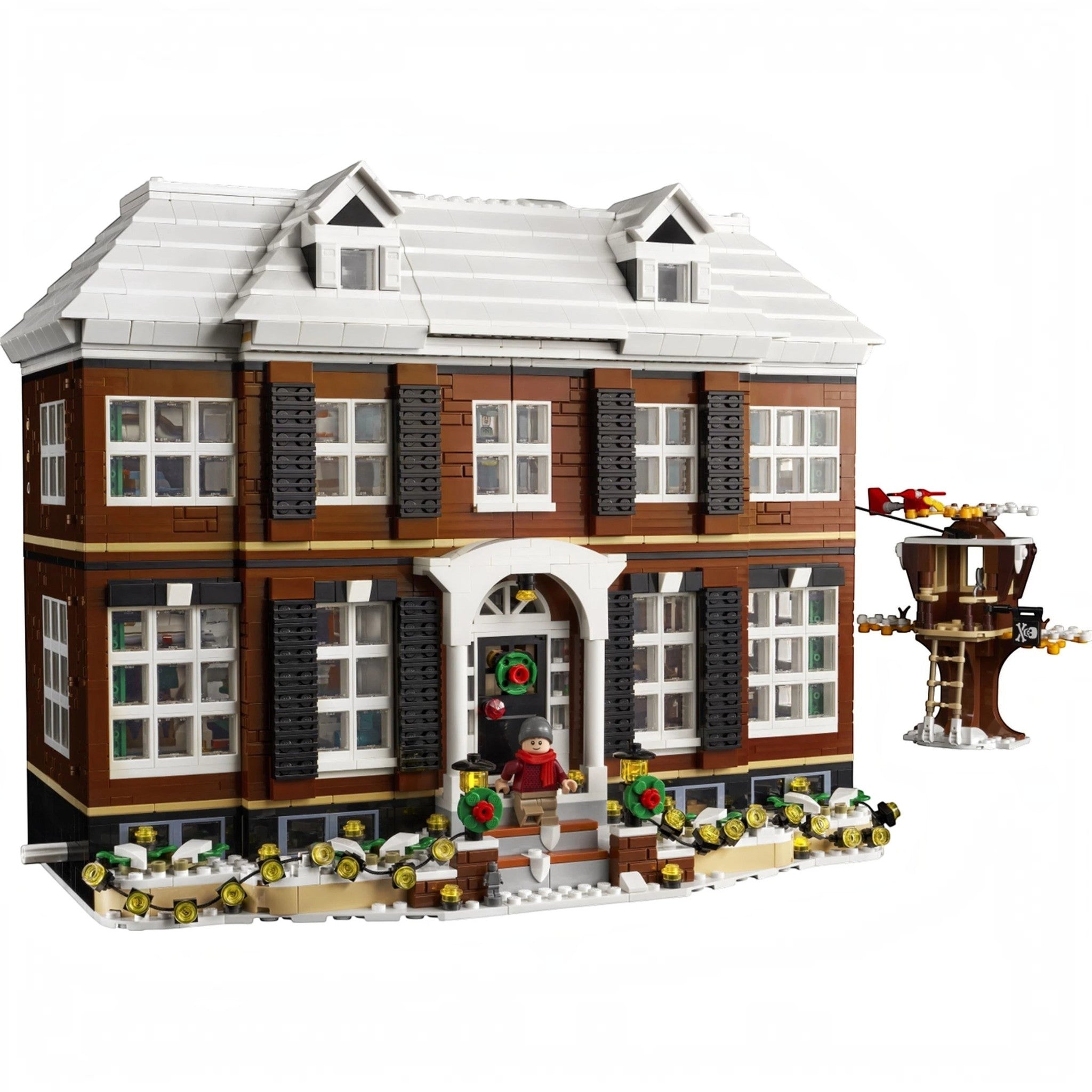 A Brick Apart LEGO Ideas Home Alone McCallisters house set with snow-covered roof, tree house, and Kevin minifigure.
