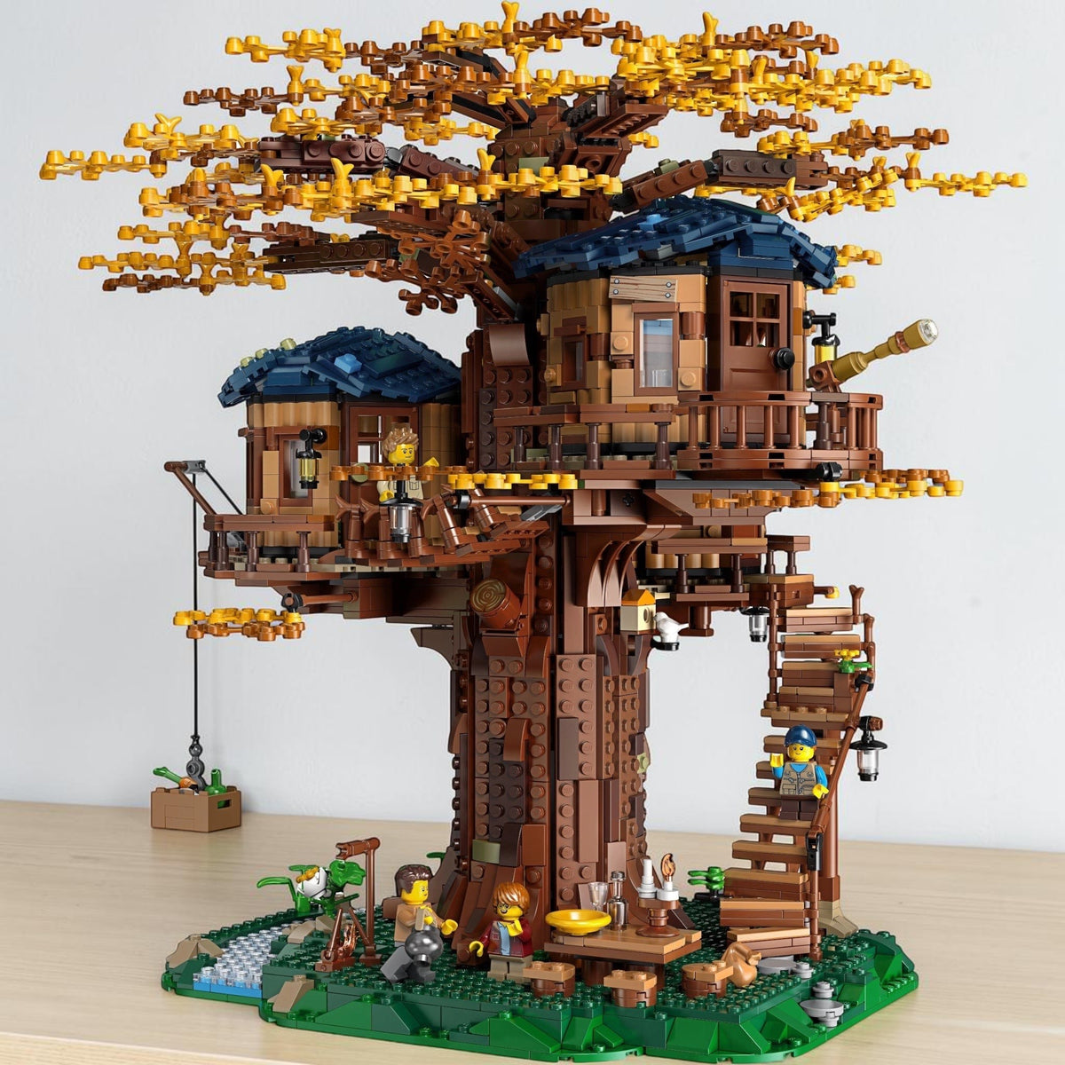 [lifestyle-shelf-built] A Brick Apart LEGO Ideas Tree House set with autumn leaves, three cabins, minifigures, and detailed landscape base.