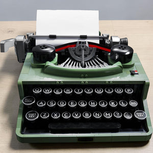 A Brick Apart LEGO Ideas Typewriter model in sand green with functional keys and a paper carriage on a white background