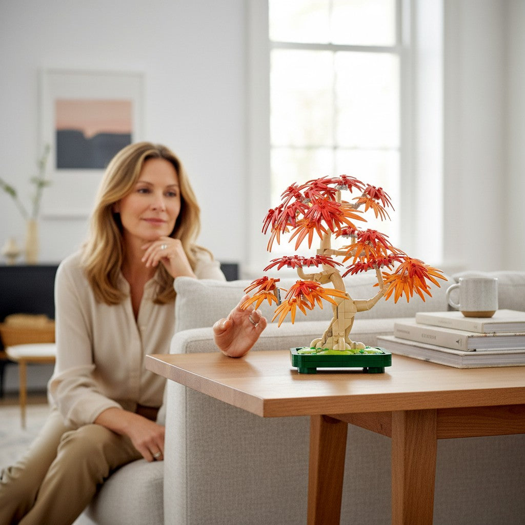 A Brick Apart LEGO Botanicals Japanese Maple Tree set displayed on a wooden table with a woman sitting in the background.