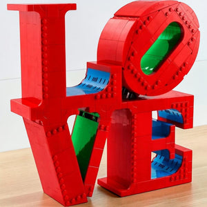 A Brick Apart LEGO Art LOVE sculpture featuring vibrant red, blue, and green bricks in a 3D display model.