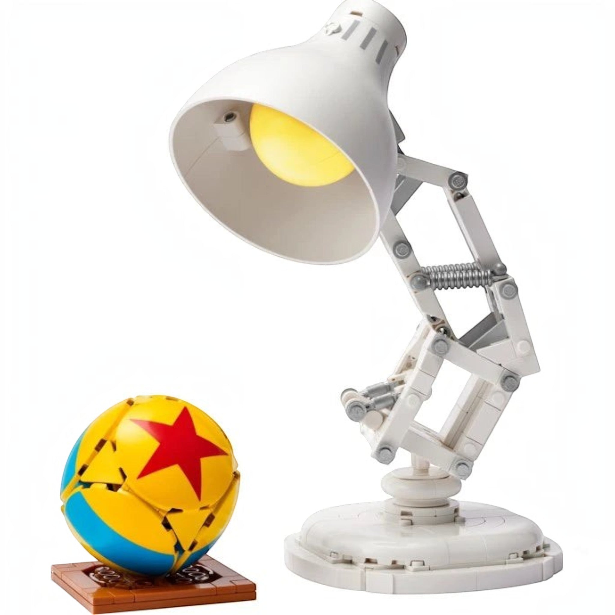 A Brick Apart LEGO Ideas Disney Pixar Luxo Jr. desk lamp model with a yellow and blue ball on a brown display stand.