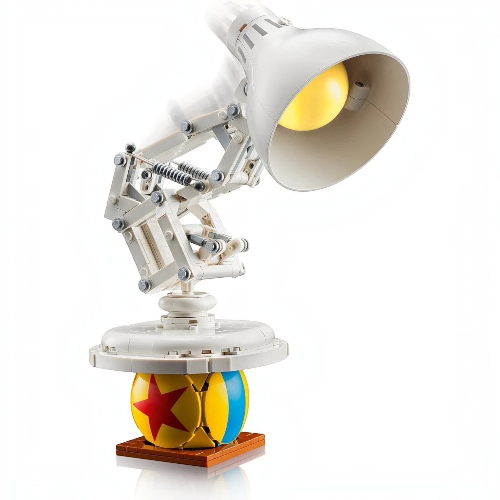 A Brick Apart LEGO Ideas Disney Pixar Luxo Jr. desk lamp model balancing on a colorful Pixar ball with articulated joints.