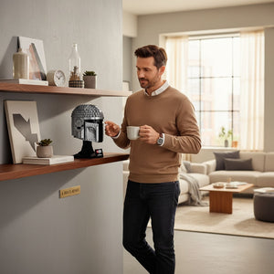 A Brick Apart LEGO Star Wars The Mandalorian helmet display model on a wooden shelf next to a man holding a mug