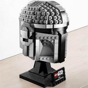 A Brick Apart LEGO Star Wars The Mandalorian helmet model featuring metallic grey beskar armor on a display stand.