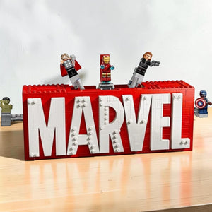 A Brick Apart LEGO Marvel logo display set featuring red and white bricks with Hulk, Thor, Iron Man, Black Widow, and Captain America minifigures.