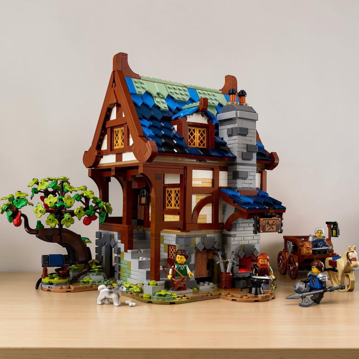 [lifestyle-shelf-built] A Brick Apart LEGO Ideas Medieval Blacksmith set featuring a detailed timber-framed workshop, apple tree, and figures.