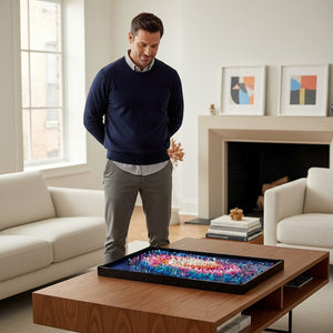 A Brick Apart LEGO Art The Milky Way Galaxy set displayed on a coffee table with a man admiring the 3D space art.